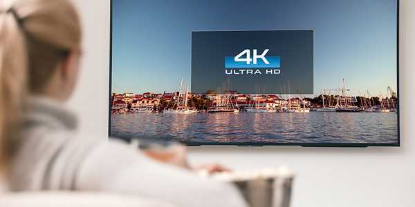 A woman watching a 4K TV in a living room.